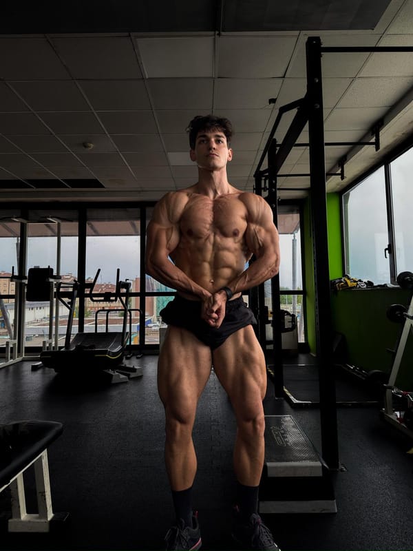 Atleta di bodybuilding in posa di controllo in sala pesi, dopo una fase di definizione.